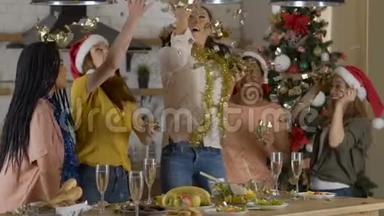 五个女朋友庆祝新年圣诞节，扔纸屑。 大房子里舒适的餐厅。 慢动作